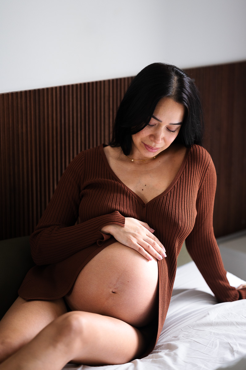 young mother to be in brown top lays on her bed