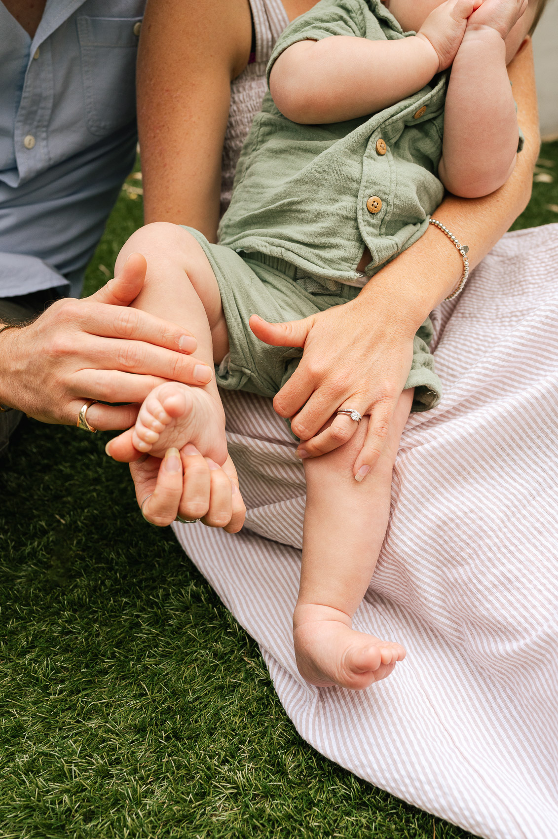 detail photo of a young family and their hands as they hold eachother